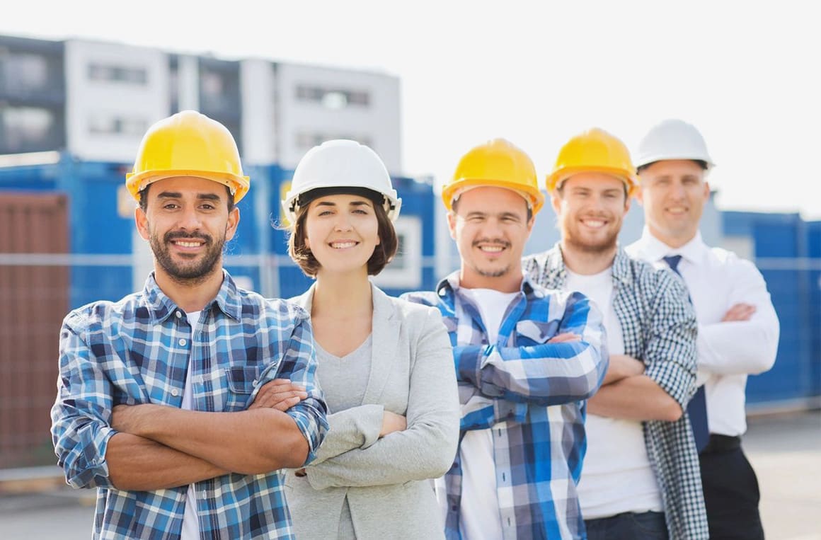 A group of people wearing hard hats and smiling.