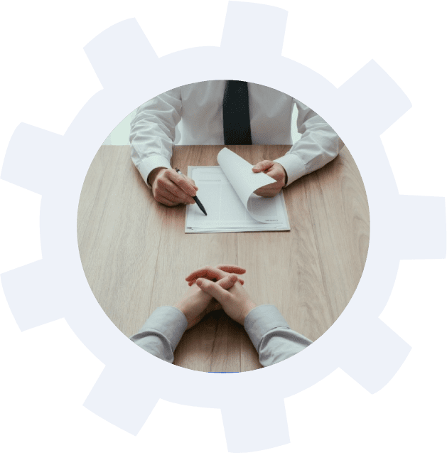 Two people sitting at a table with papers and pens.